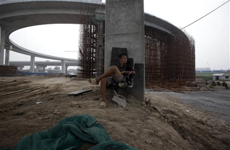 A Chinese man rests by loop of a highway under construction in Beijing, China. China is set to overtake Japan as the world's second largest-economy.